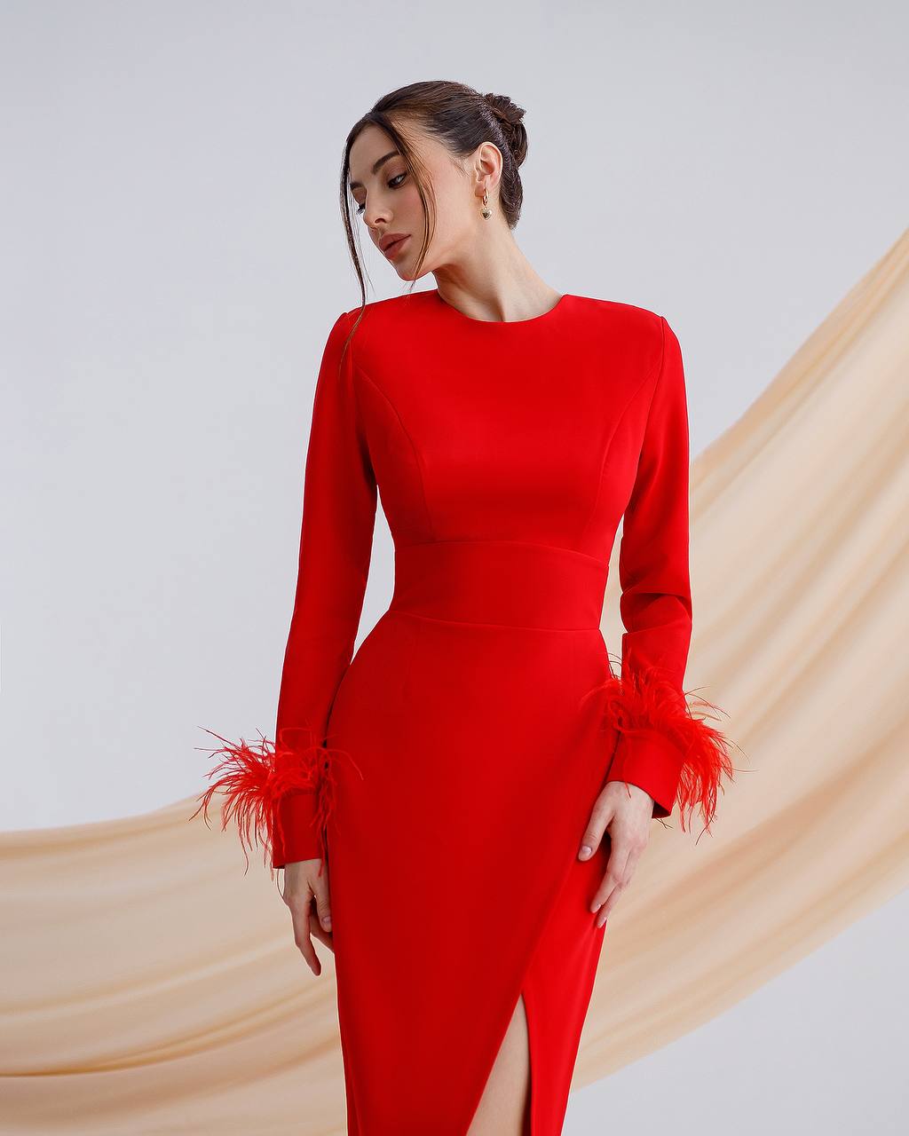 a woman wearing a red dress with feathers on the side
