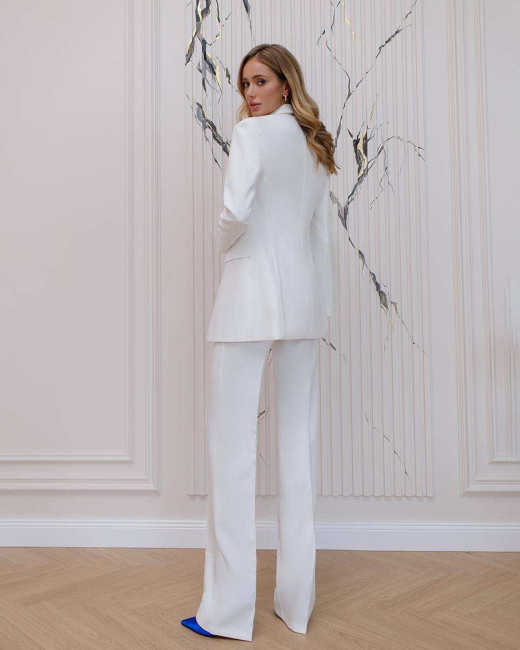 a woman wearing a white suit and blue shoes
