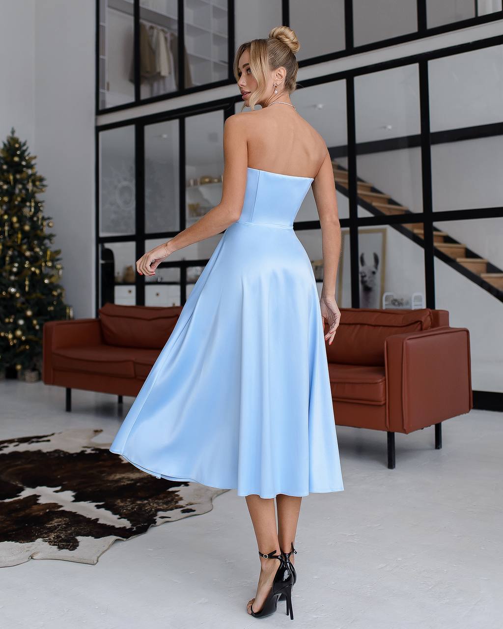 a woman in a blue dress standing in front of a christmas tree