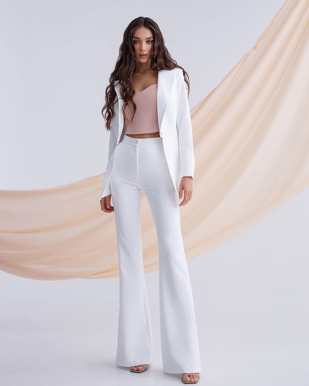a woman wearing a white suit and pants