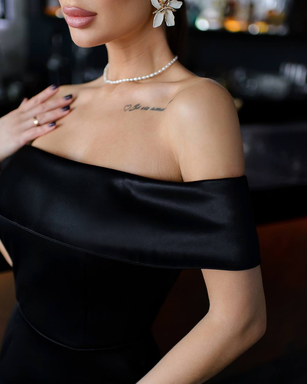 a woman in a black dress with a flower on her shoulder