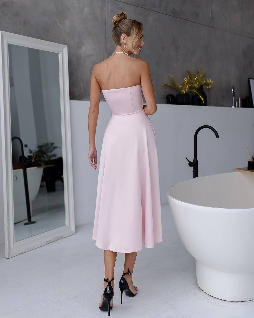 a woman in a pink dress standing in front of a mirror