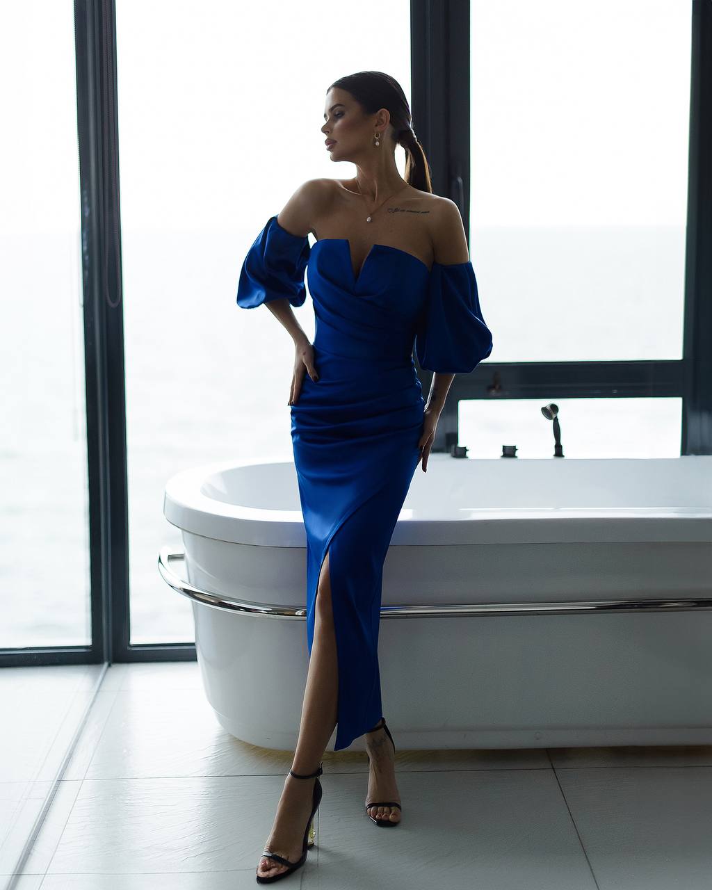 a woman in a blue dress standing in front of a tub