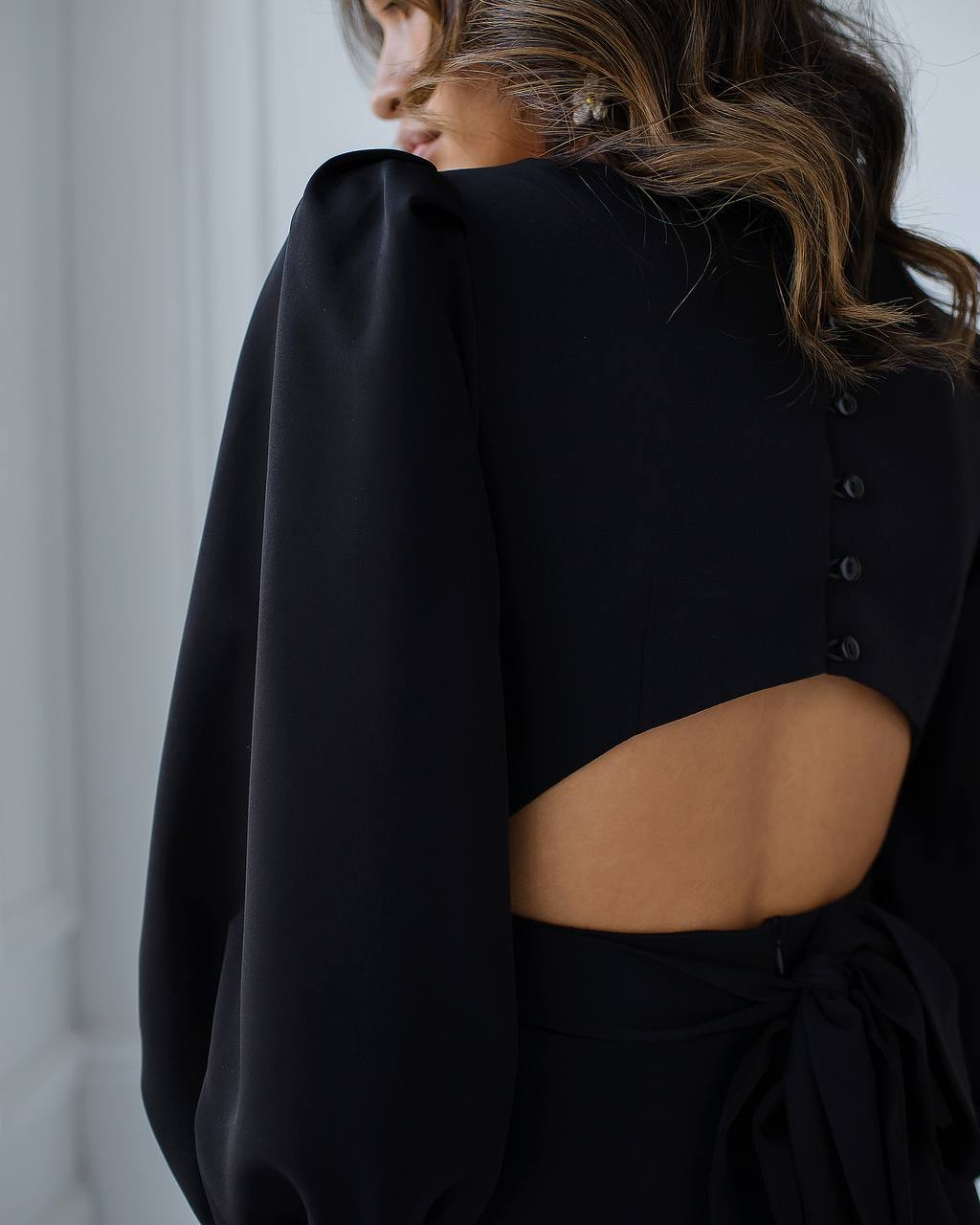 a woman wearing a black dress with a cut out back