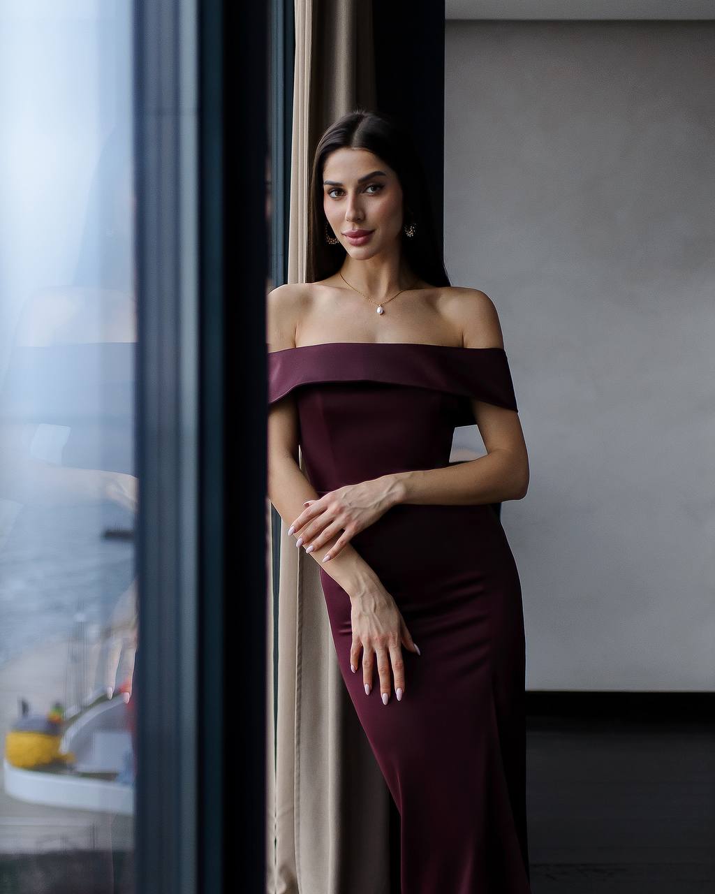 a woman in a long dress leaning against a wall