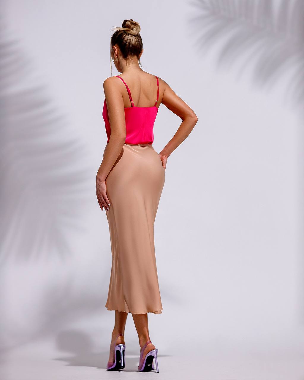 a woman in a pink top and tan skirt