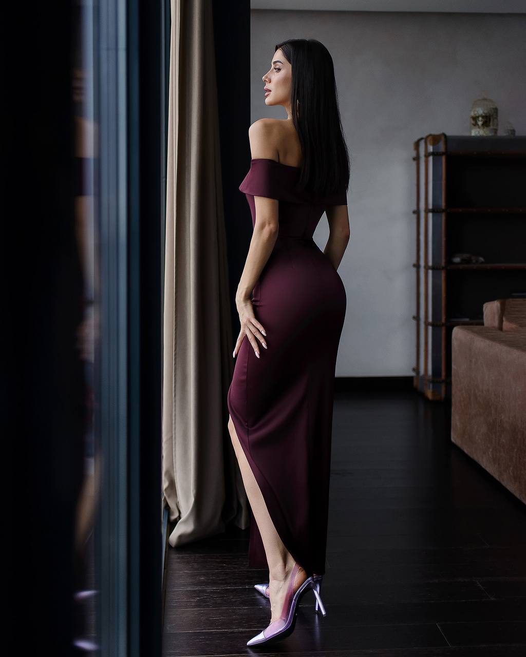 a woman in a purple dress standing in front of a window