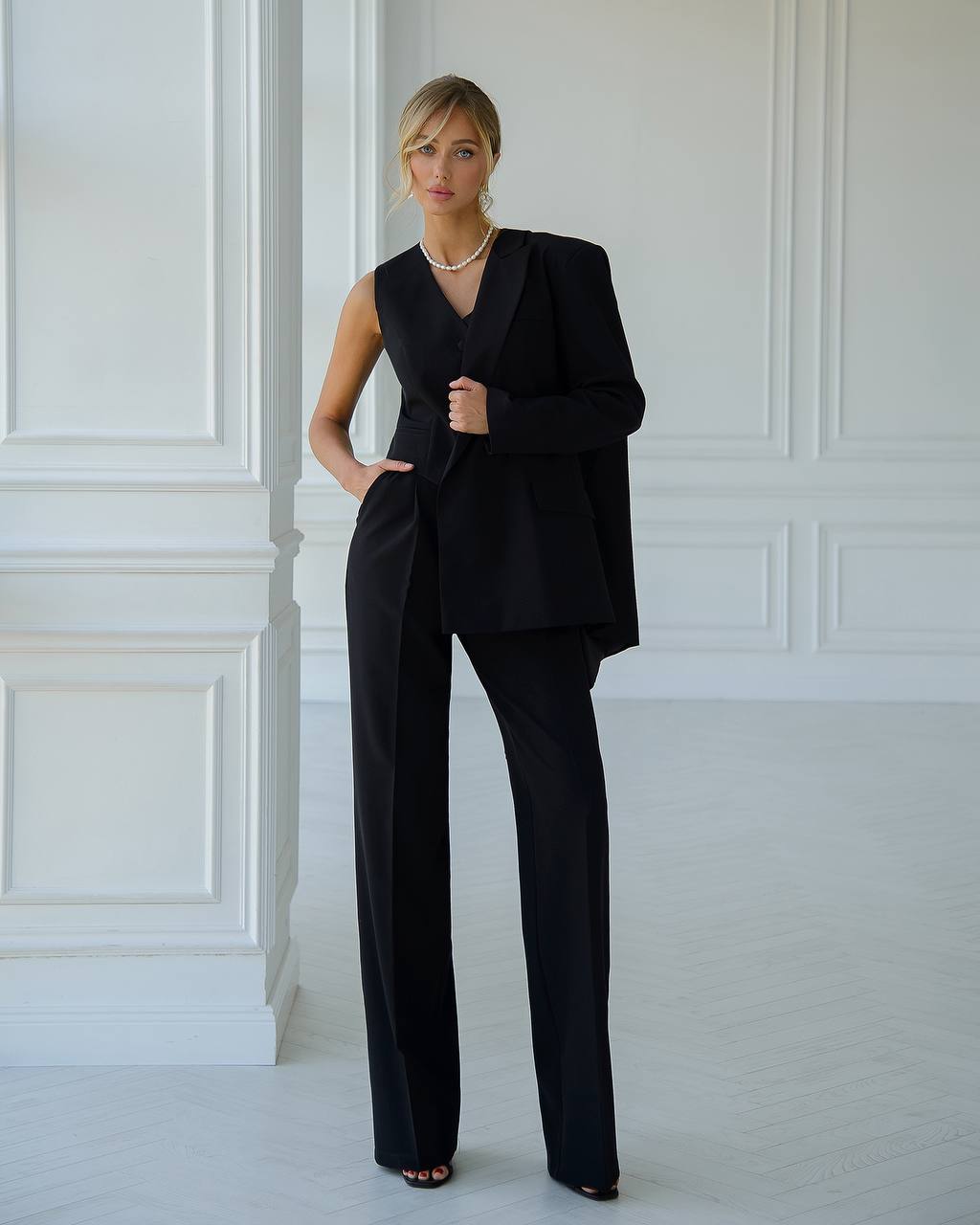 a woman in a black suit standing in a white room