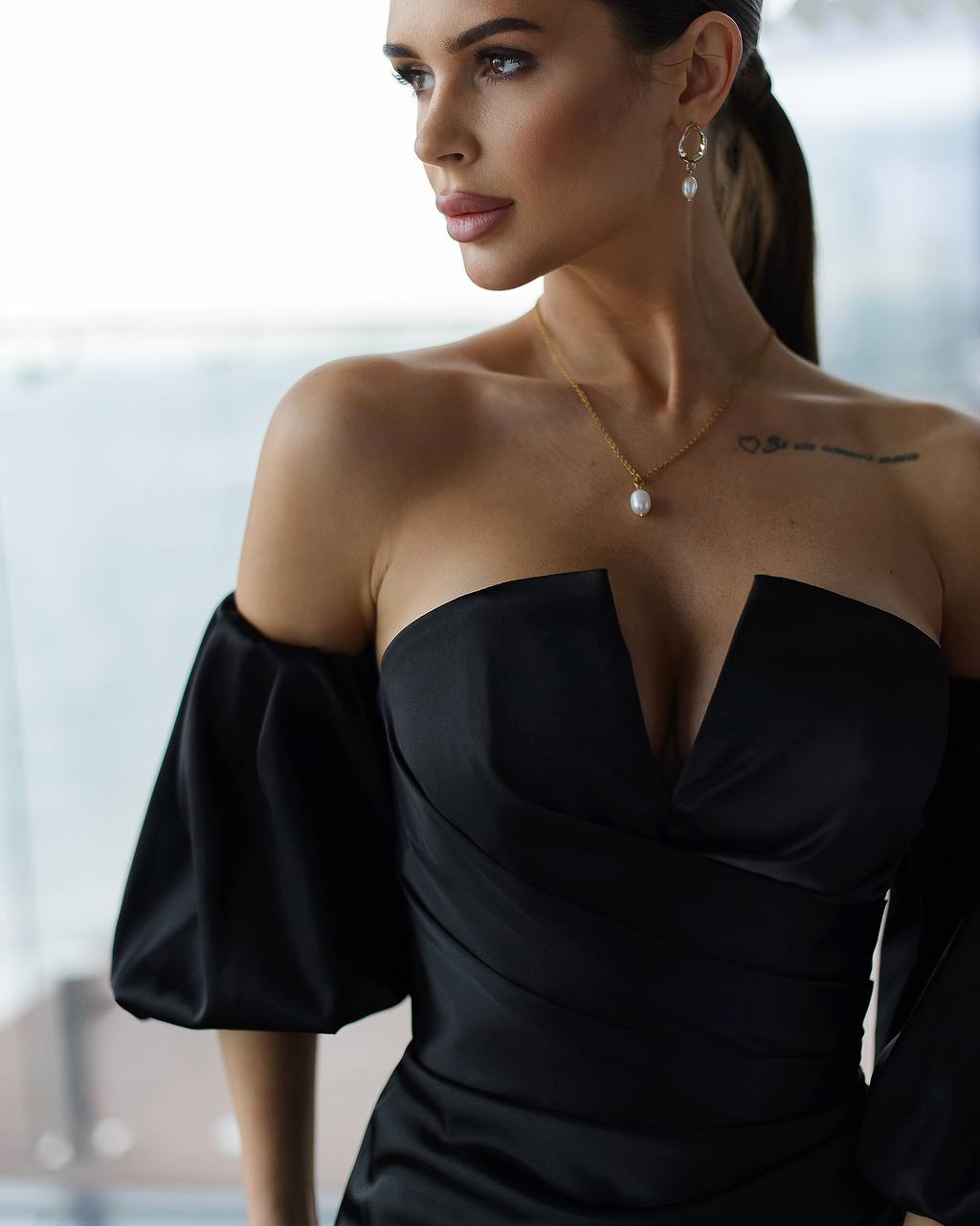 a woman wearing a black dress and a pearl necklace