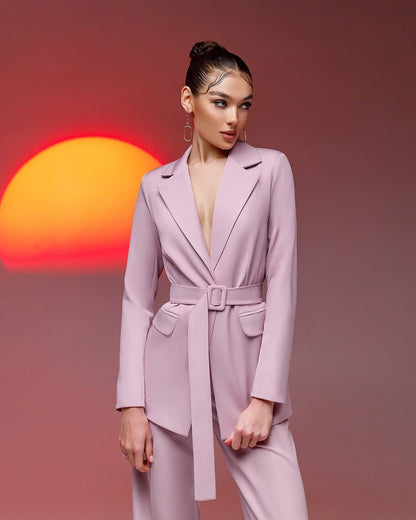a woman in a pink suit standing in front of a sunset