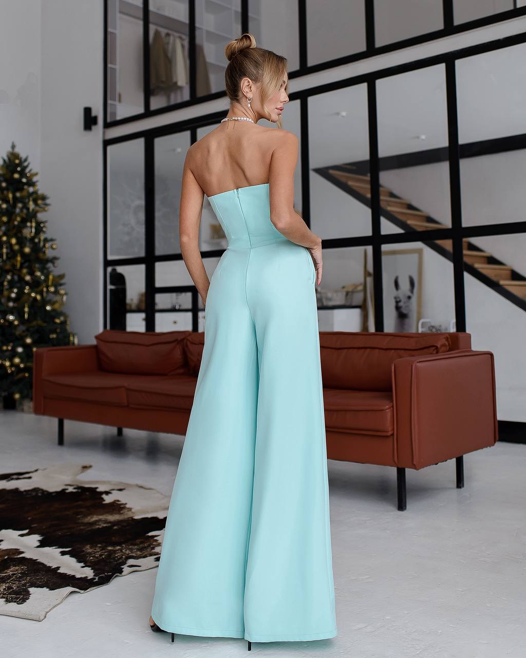 a woman in a strapless blue jumpsuit standing in a living room
