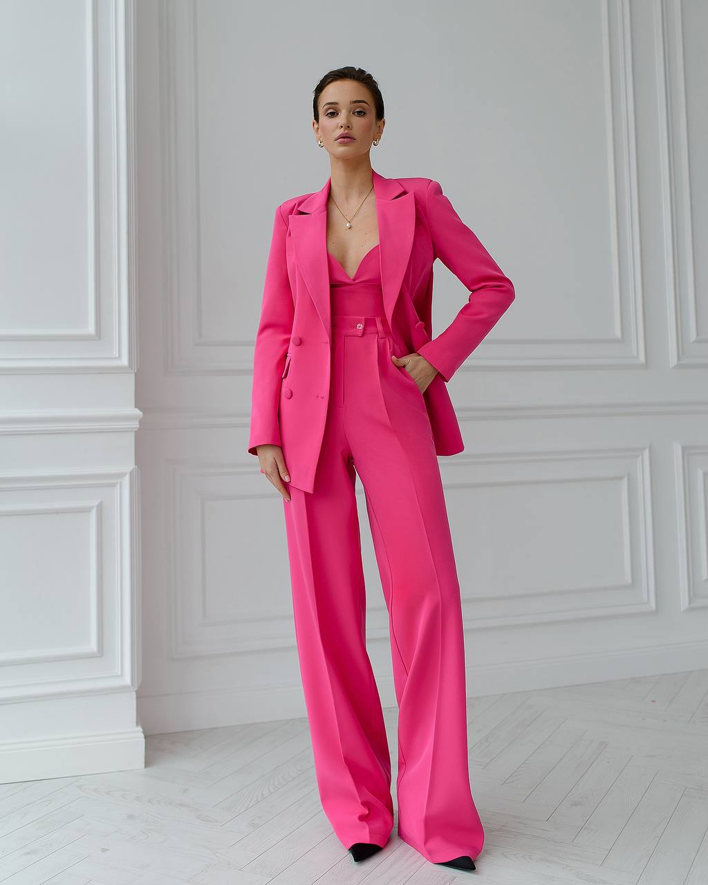 a woman in a pink suit standing in a white room