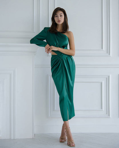 a woman in a green dress leaning against a wall