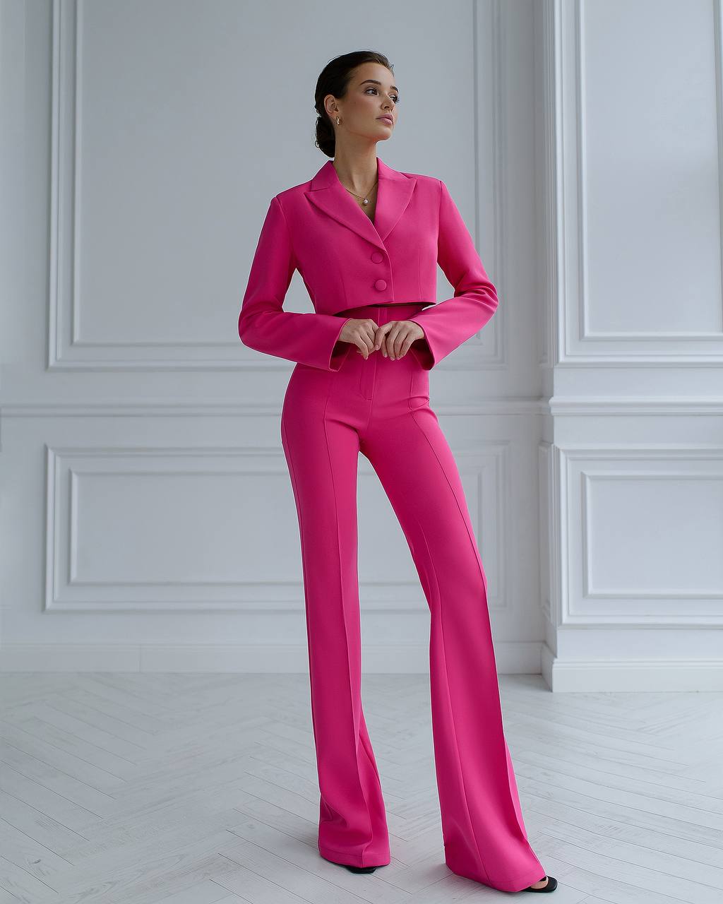 a woman in a pink suit standing in front of a white wall