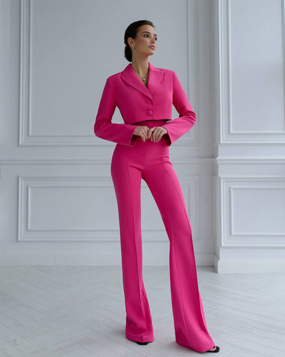 a woman in a pink suit standing in front of a white wall