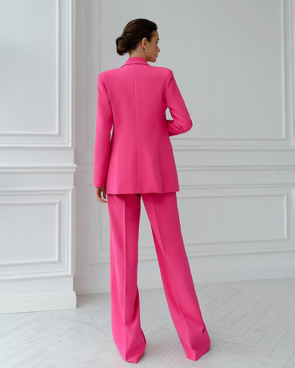 a woman in a bright pink suit stands in a white room
