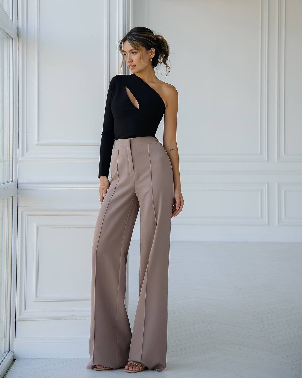 a woman in a black top and tan pants