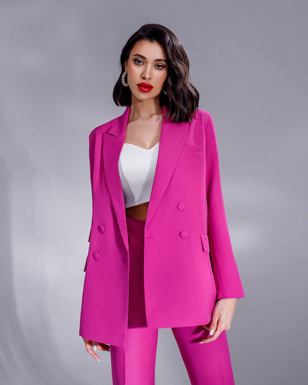 a woman in a bright pink suit posing for a picture