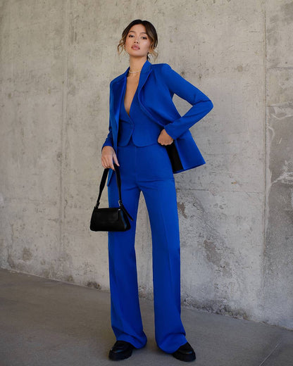 a woman wearing a blue suit and holding a black purse