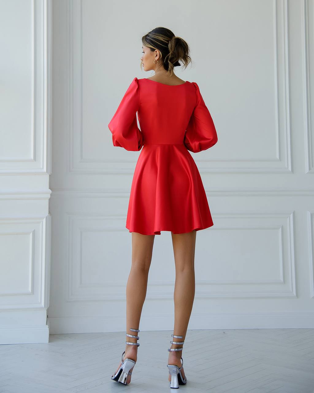 a woman in a red dress standing in front of a white wall