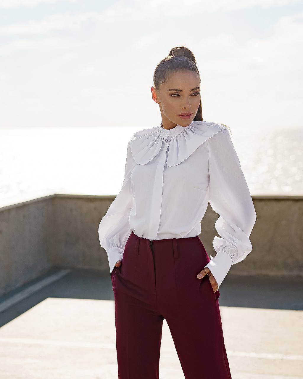 a woman wearing a white shirt and maroon pants