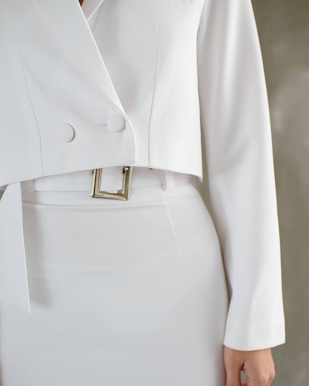 a woman wearing a white suit and belt