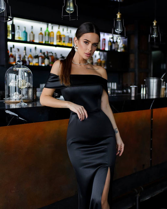 a woman in a black dress standing in front of a bar