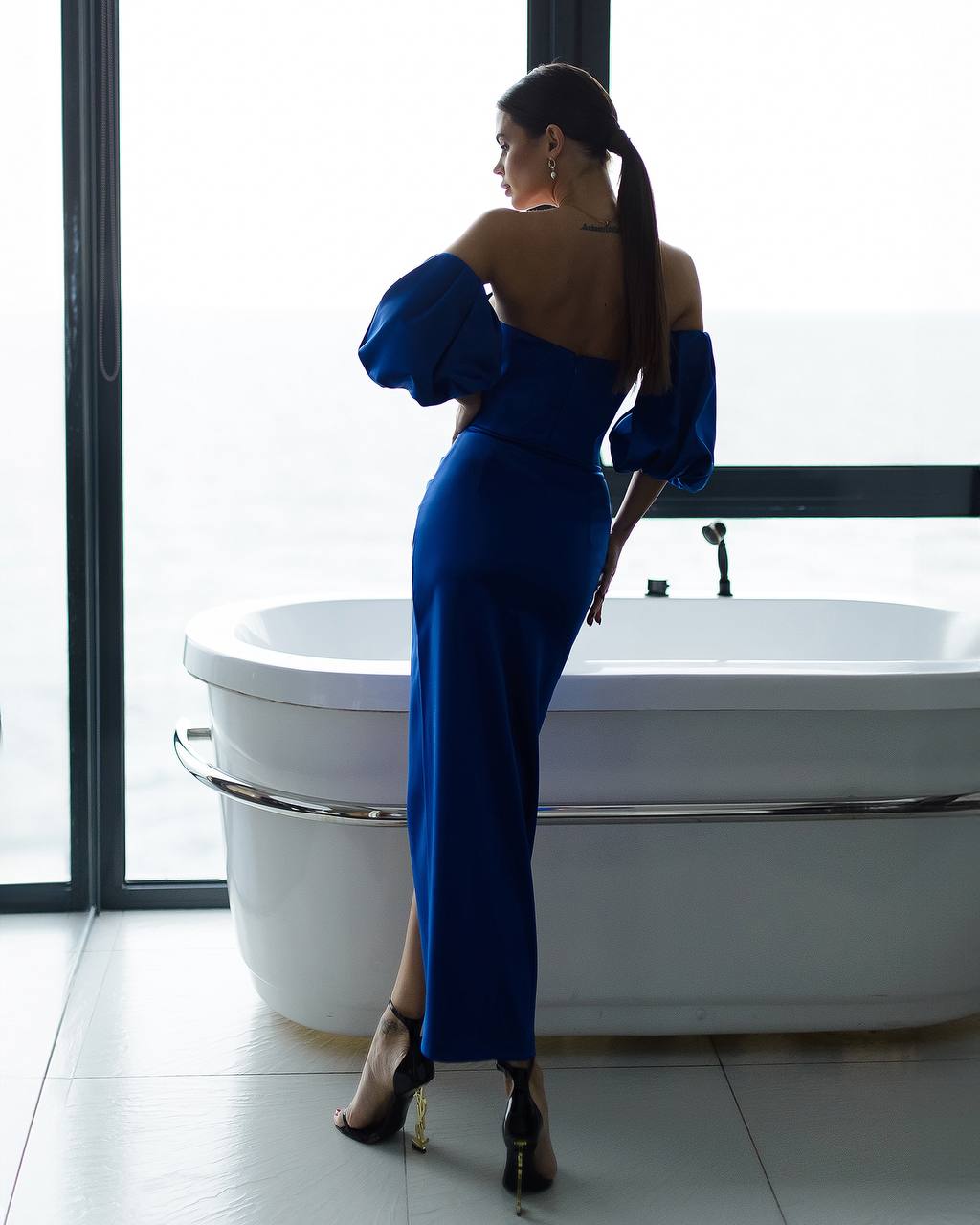 a woman in a blue dress standing in front of a tub