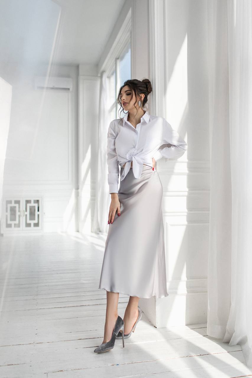 a woman in a white shirt and grey skirt