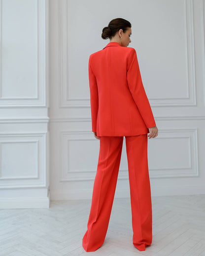 a woman in a red suit stands in a white room