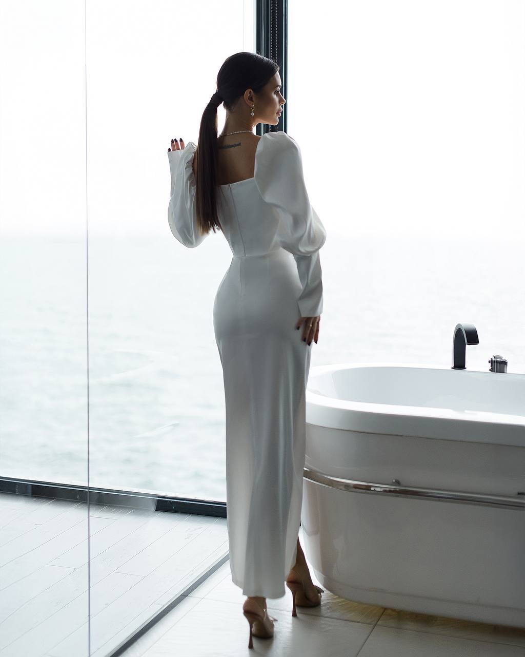 a woman in a white dress standing in front of a bathtub
