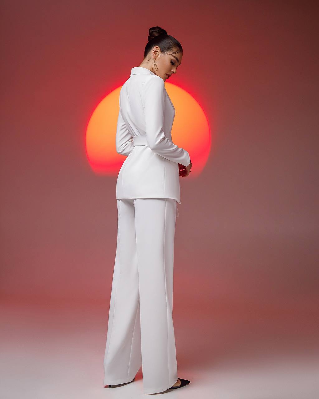 a woman in a white suit standing in front of a red sun