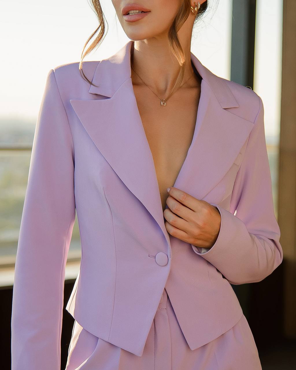 a woman wearing a purple suit and a necklace