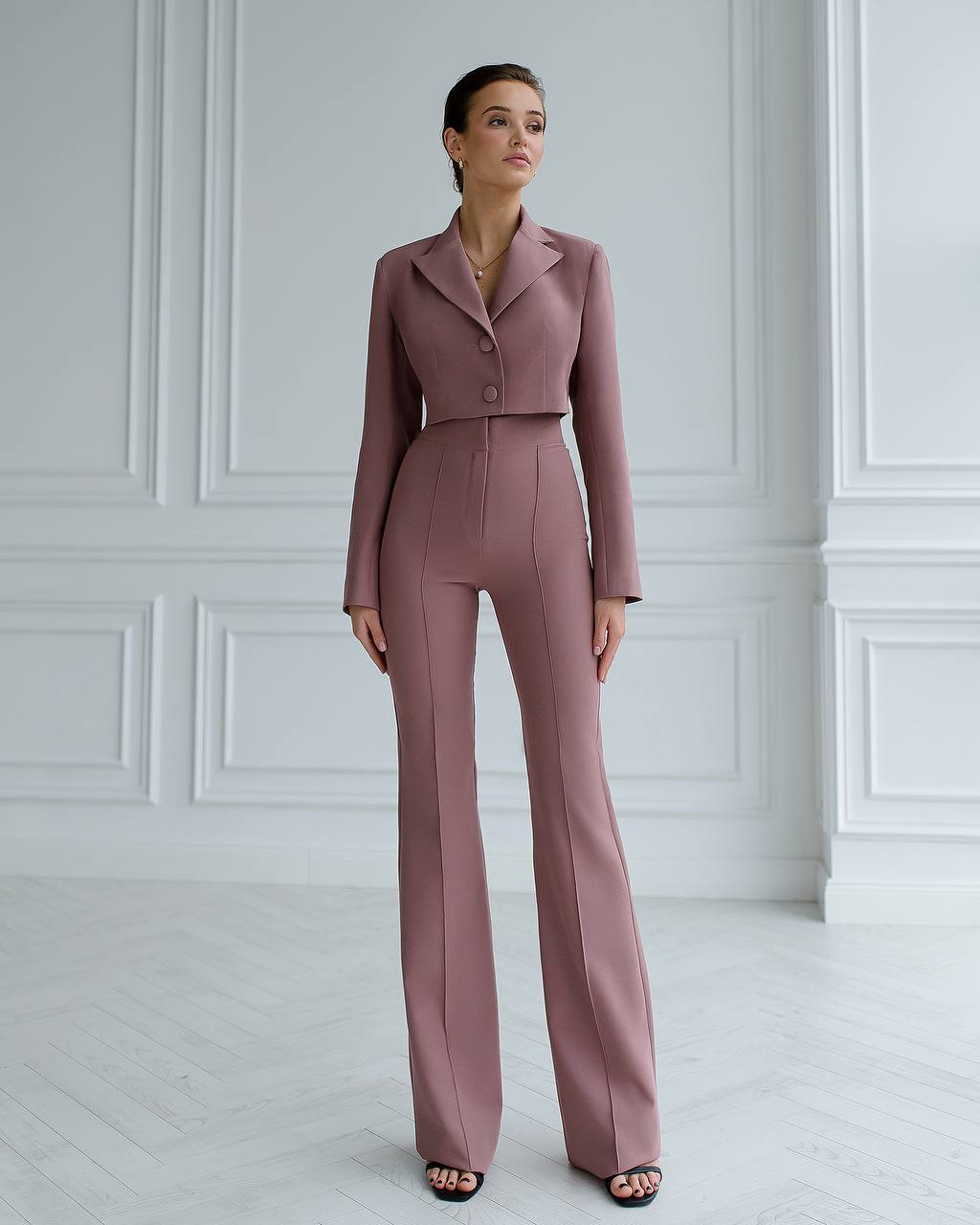 a woman in a pink suit stands in a white room