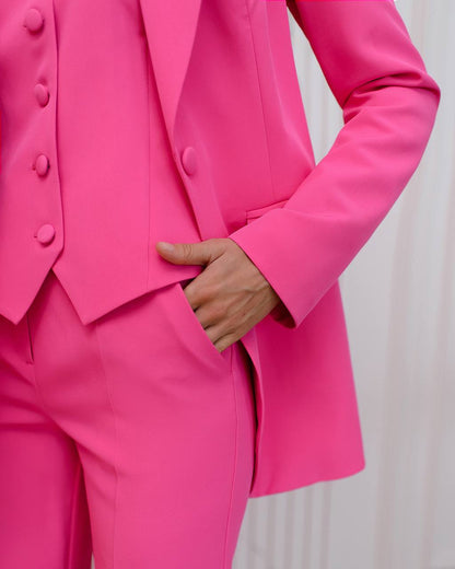 a woman in a bright pink suit is holding her hand on her hip