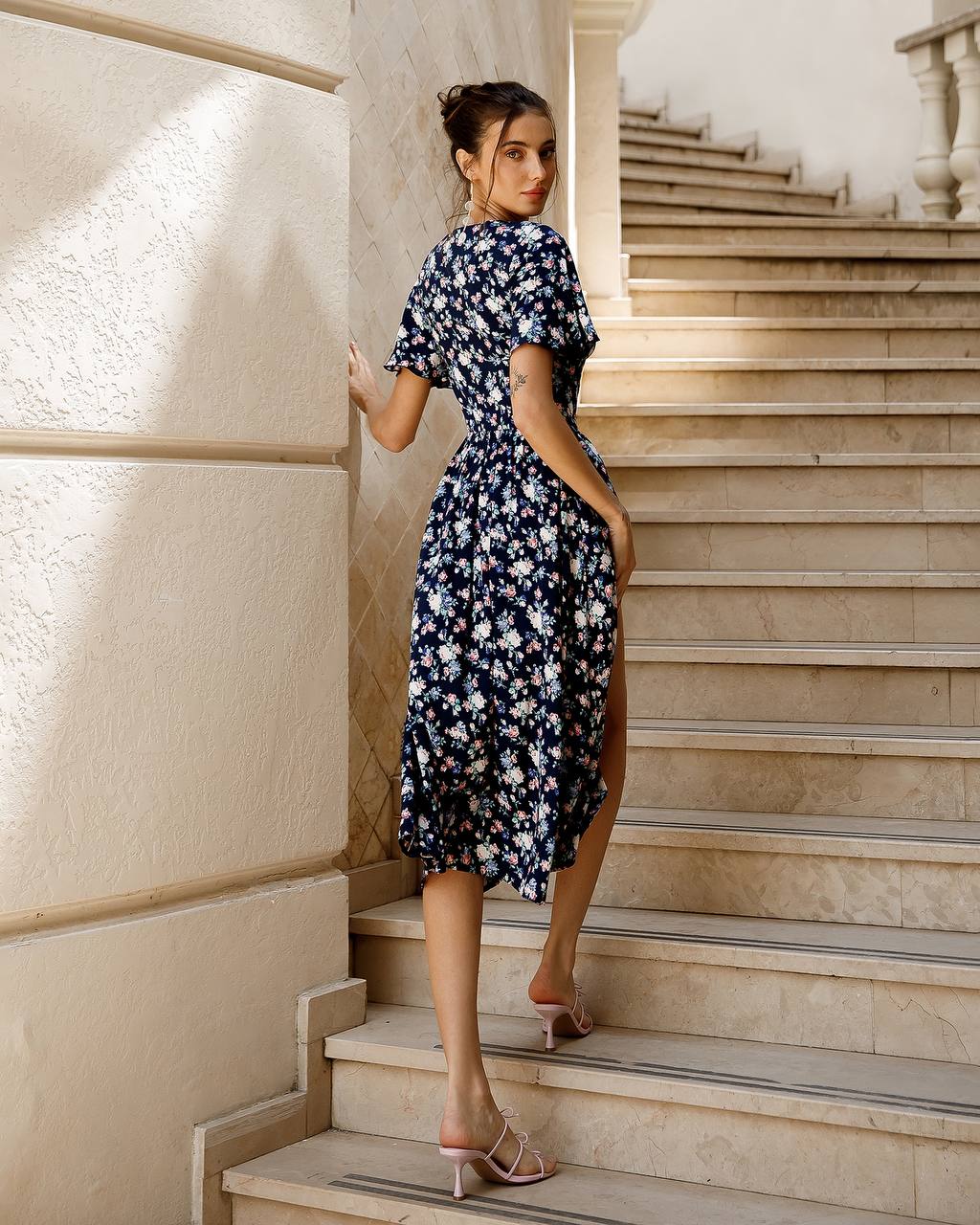 a woman in a blue dress is standing on some steps