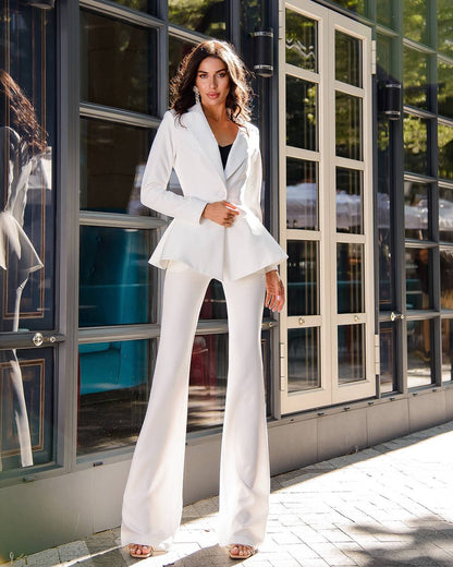 a woman in a white suit standing outside of a building