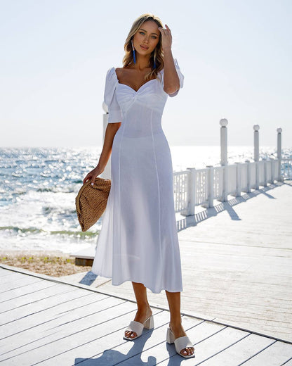 a woman in a white dress standing on a pier