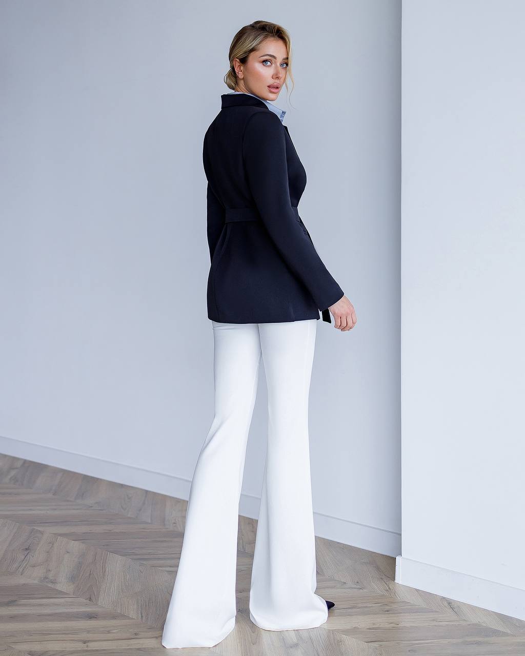 a woman in a black jacket and white pants