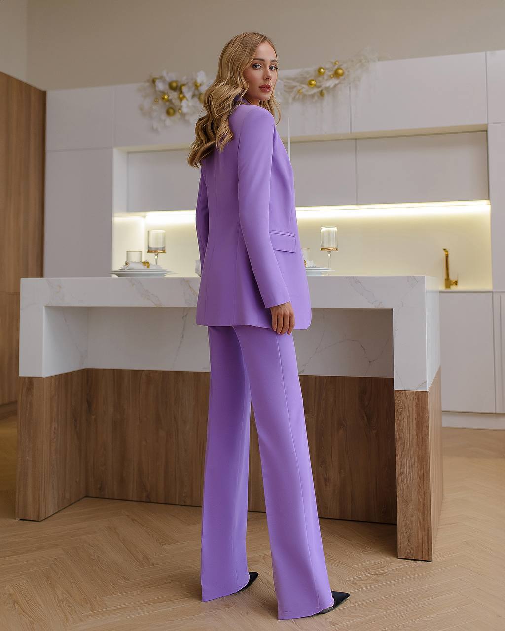 a woman in a purple suit standing in front of a counter