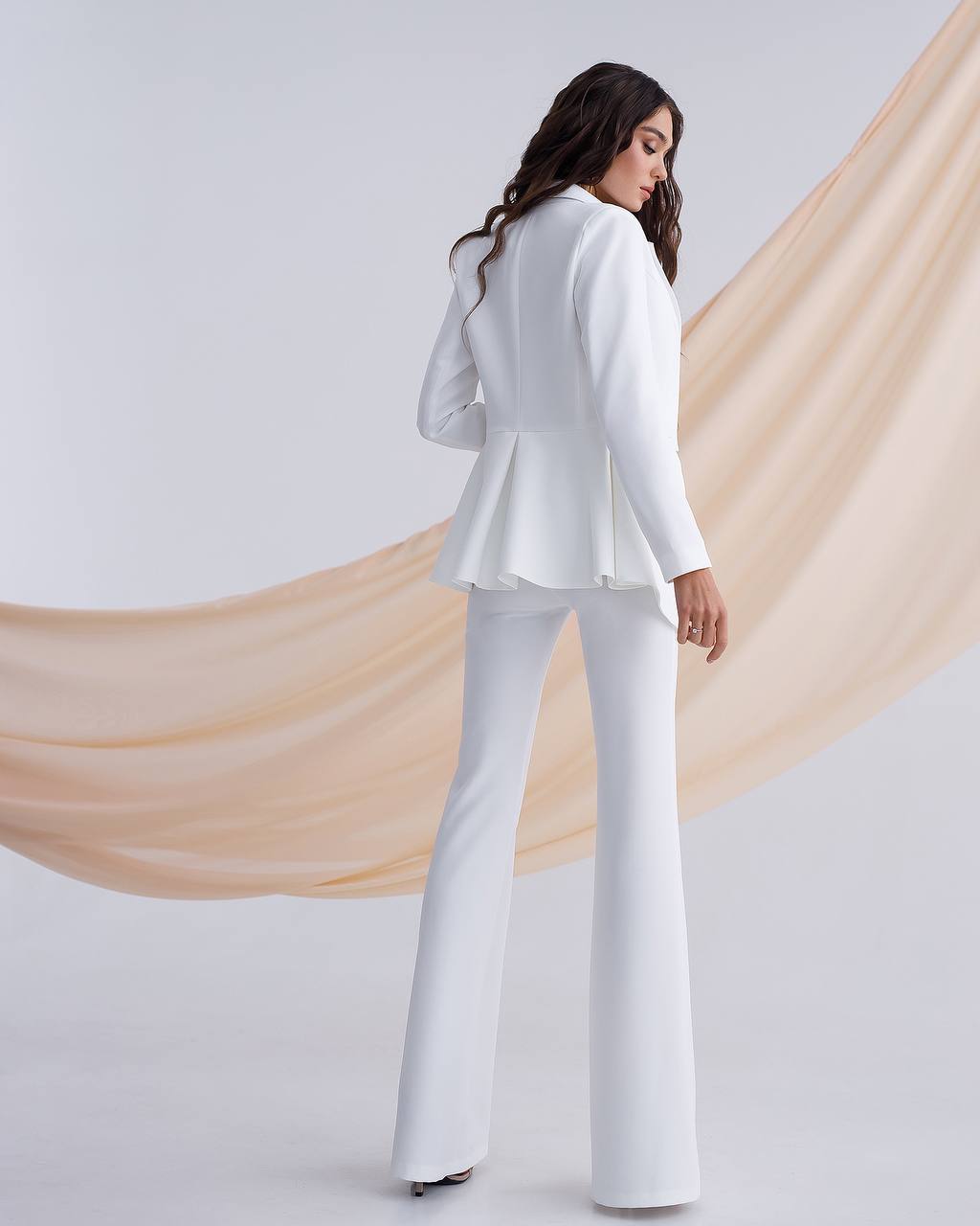 a woman wearing a white suit and pants