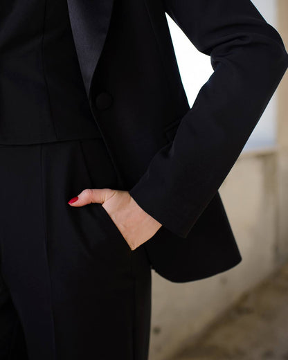 a woman wearing a black suit and red nails