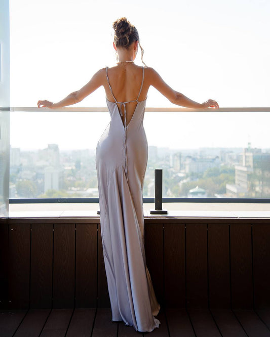 a woman in a long dress looking out a window
