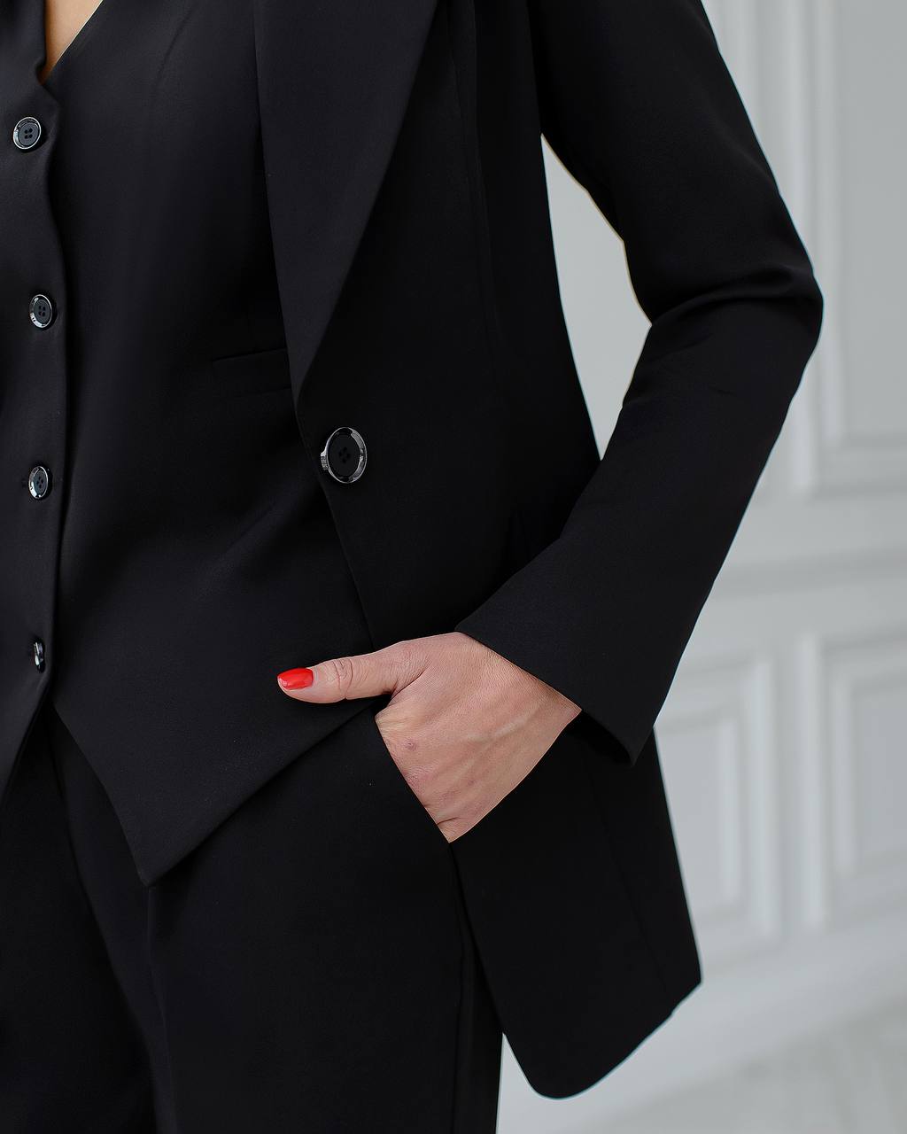 a woman in a black suit with a red nail polish