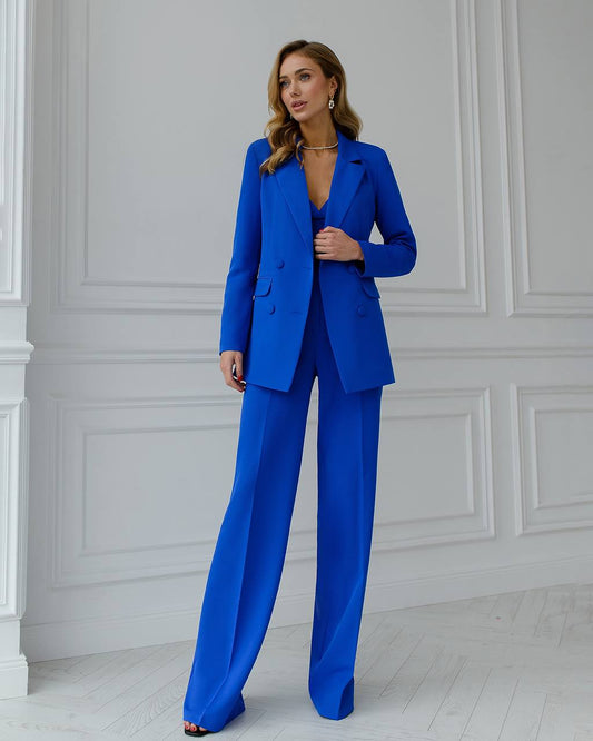 a woman in a blue suit standing in front of a white wall