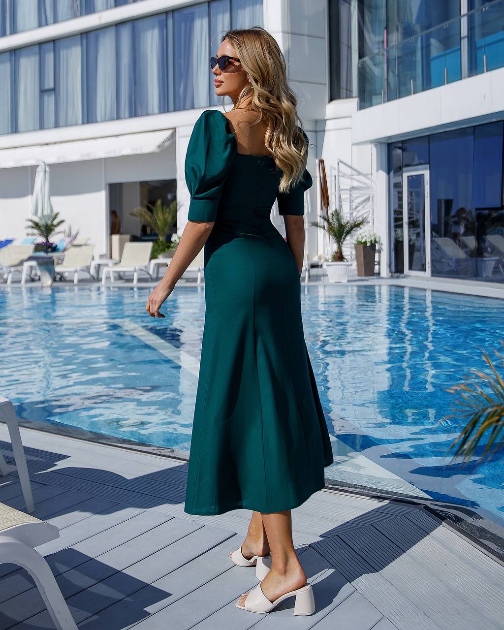 a woman in a green dress standing by a pool