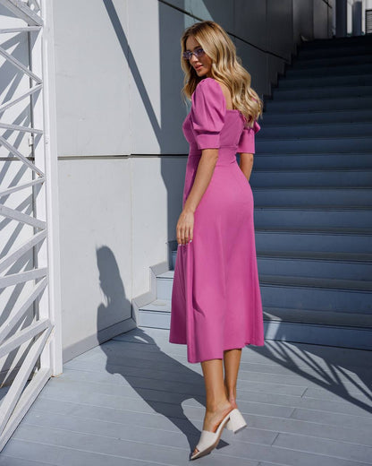 a woman in a pink dress standing in front of stairs