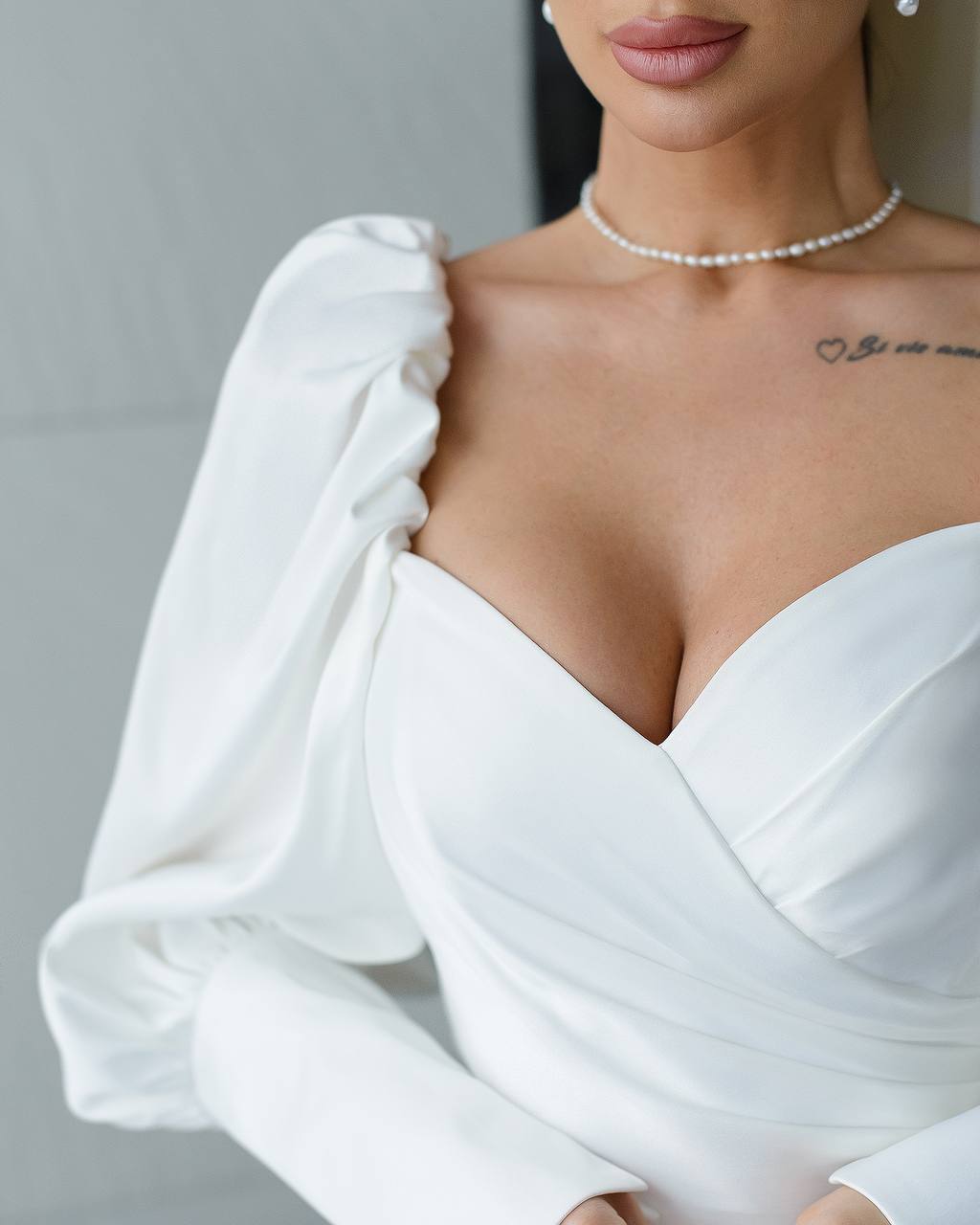 a woman in a white dress with a tattoo on her chest