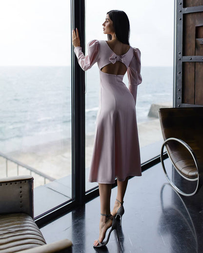 a woman in a pink dress looking out a window
