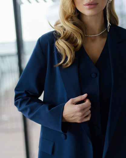 a woman in a blue jacket and a pair of earrings